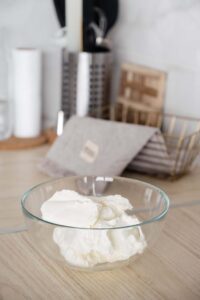 Homemade cream cheese in a class bowl sitting on the kitchen counter.