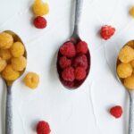 Gold berries and red raspberries on a spoon.