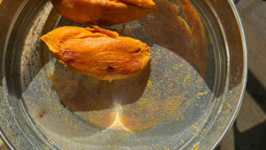 Peeled sweet potatoes on a stainless steel sieve