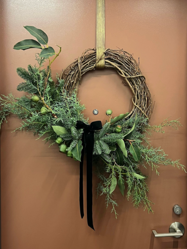 A Whimsical Christmas wreath hanging on a door.